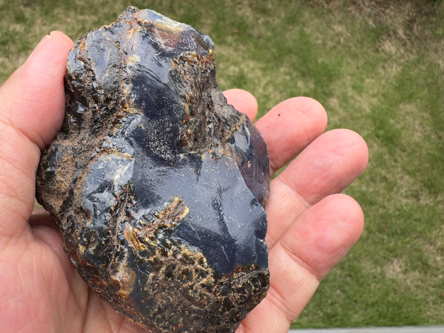手のひらサイズのブルーアンバー原石。表面には細かな植物の痕跡のような模様が刻まれ、蒼とこげ茶が混ざり合う静かな雰囲気